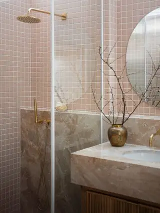 koralová kúpeľňa so sprchovacím kútom a umývadlom s mramorovou doskou. sklenené dvere