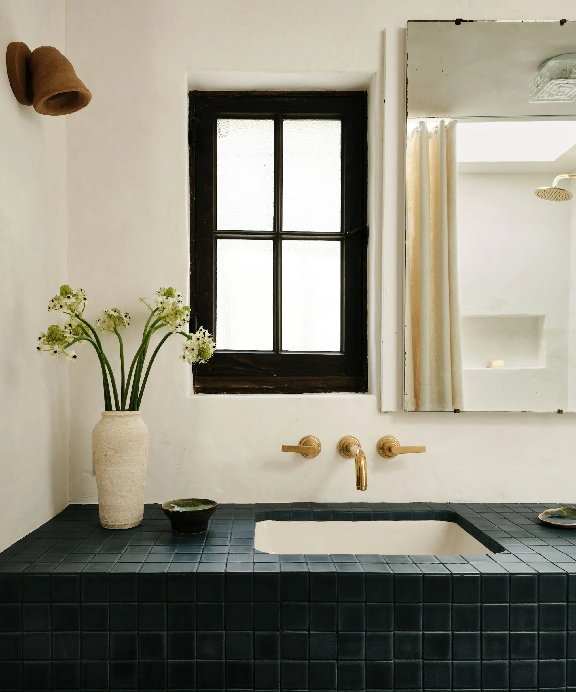 חדר אמבטיה אדוב עם קירות גבס איפור אריחים וארון תרופות על הקיר' loading='lazy' title=