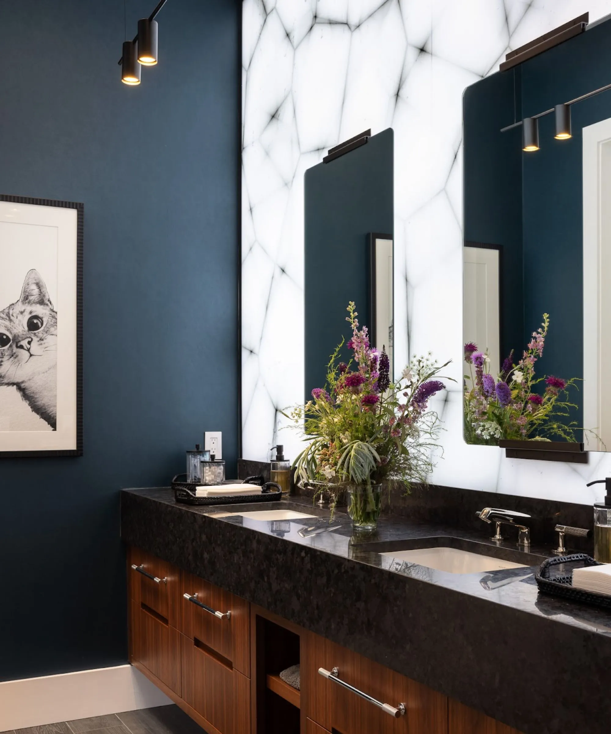 חדר שינה אורח עם קירות כחולים כהים יהירות עץ עם משטח שולחן שחור קיר תאורה ויצירות אמנות של חתול ממוסגר על הקיר' loading='lazy' title=