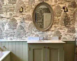 Une salle de bains avec des boiseries vertes et un papier peint classique à motifs monochromes