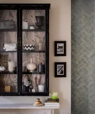 Gros plan d'une vitrine en verre noir montée sur un mur rose clair à côté de carreaux muraux bleus à chevrons