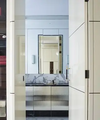 숨겨진 문이 있고 화장대 위에 대형 벽 거울이 있는 전용 욕실