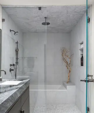 Salle de bains avec douche carrelée à l'italienne avec carrelage en marbre et paroi en verre, meuble de salle de bain noir avec comptoir en marbre gris