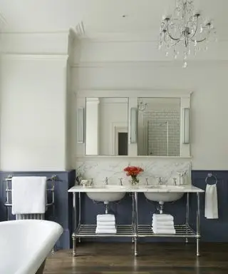 Une salle de bain avec lustre, boiseries bleues et double vasque