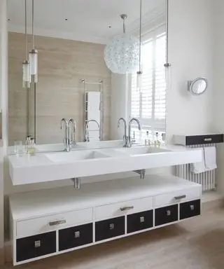 Une salle de bain neutre avec une double vasque blanche et un grand lustre sphérique blanc