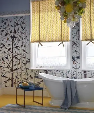 Une salle de bain avec du papier peint à motifs jaunes et bleus et un lustre en verre soufflé