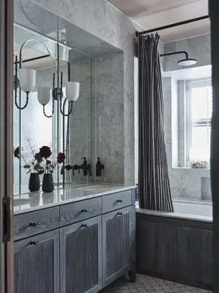 대리석 타일로 마감하고 회색 목재 세면대가 설치된 욕실