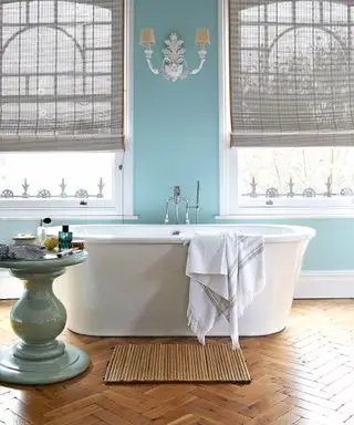 Une baignoire îlot blanche sur parquet en bois devant un mur bleu
