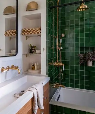 Salle de bain blanche avec quincaillerie dorée et douche carrelée brillante