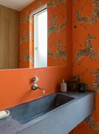 Salle de bain avec papier peint orange et vasque en pierre