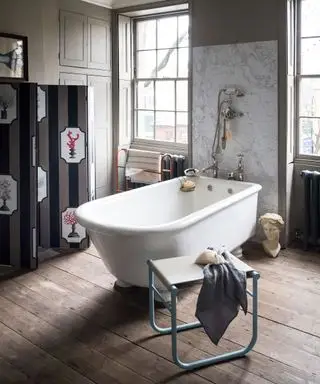 Banheiro cinza com piso de madeira e banheira independente