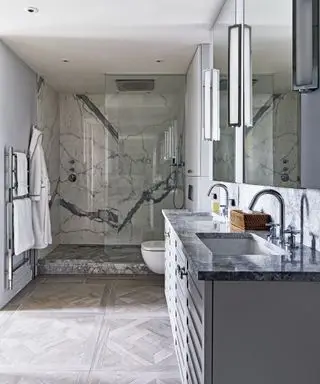 Banheiro cinza com piso em parquet e parede de mármore