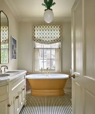 Salle de bains de style vintage avec carrelage à rayures et baignoire autoportante peinte en jaune