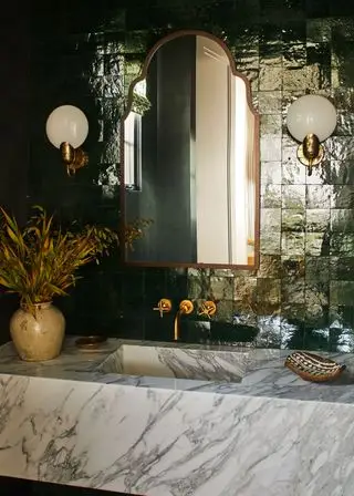 Lavabo de salle de bains en marbre avec carreaux verts réfléchissants et grand miroir en laiton