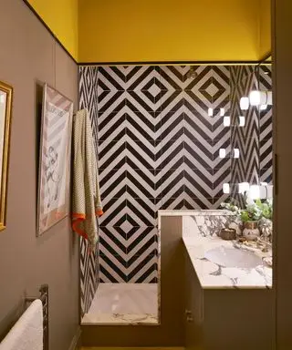 cuarto de baño amarillo y gris pardo con azulejos geométricos en blanco y negro