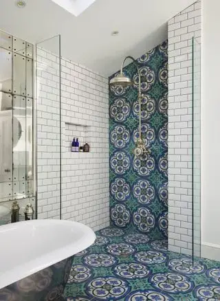 Azulejos azules de estilo marroquí en ducha, bañera y pared con espejos.