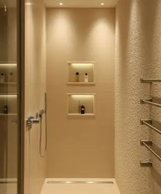 Bruser i badeværelse med tekstureret, crememalet væg, to integrerede brusenicher, fire spots i loftet