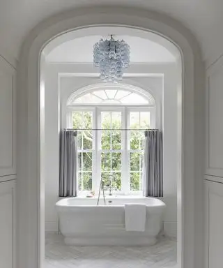 Idées de rideaux de salle de bain avec un demi-rideau gris sur une fenêtre cintrée, avec une baignoire à côté