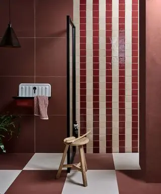 Salle de bain rouge avec carrelage rayé dans la douche à l'italienne