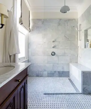 Un exemple de conception d'une salle de bain montrant une grande douche à l'italienne avec un carrelage mural gris et un siège de douche