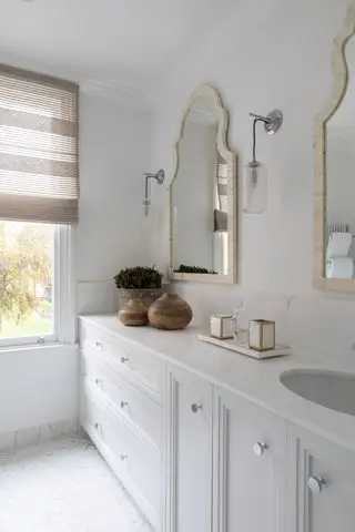 bagno bianco con piano in marmo, doppi specchi, tende cieche, armadi bianchi