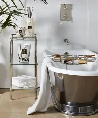 Un bagno con vasca freestanding in metallo, porta accessori e porta vasca