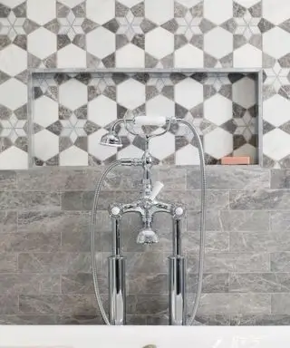 Carrelage de salle de bain gris de Claybrook derrière une pomme de douche argentée.