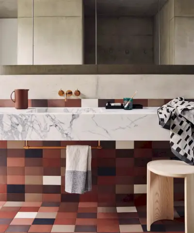 Etagère modulable blanche par String Furniture. Étagère positionnée au-dessus d'un petit évier, articles de toilette et serviettes rangés sur l'étagère, armoire avec portes miroir