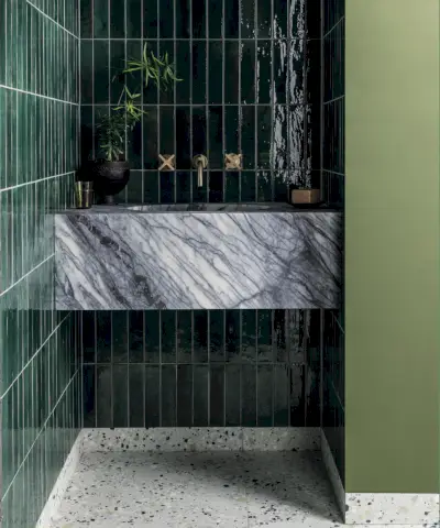 Salle de bains au thème pastel, carreaux géométriques bleus et blancs, mélange de différentes formes et couleurs de carreaux sur les murs, murs peints dans une gamme de couleurs pastel, grande vasque blanche avec deux lavabos et miroirs en arc, applique murale sur miroirs, baignoire rose