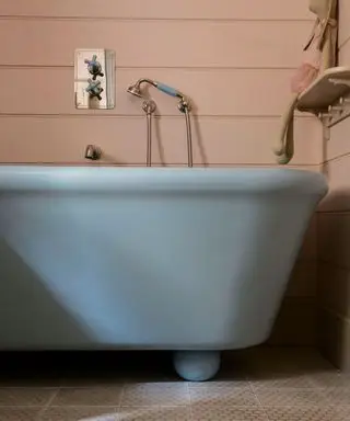 Salle de bains bleue avec murs en panneaux roses et baignoire bleue