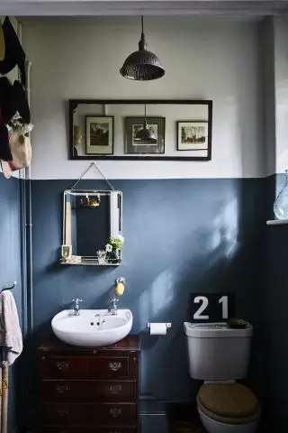 Une salle de bains blanche et bleue dans une propriété d'époque avec un lavabo blanc et un panneau 21 au-dessus des toilettes