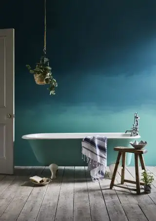 Un effet mural ombré bleu et vert dans une salle de bain avec une baignoire peinte en vert