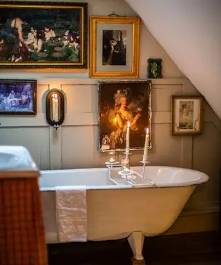 独立した再生バスと壁に古い絵画のあるヴィンテージのバスルーム