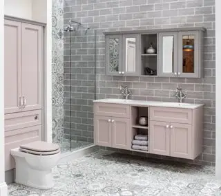 Badezimmer mit Doppelwaschtisch in Rosa mit grauen Wandschränken darüber, Schrank über WC, Dusche, gemusterten Bodenfliesen und grauem Fliesenboden