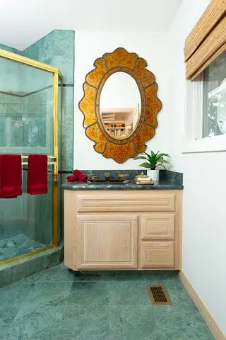 miroir antique doré dans la salle de bains avec carrelage vert et murs blancs