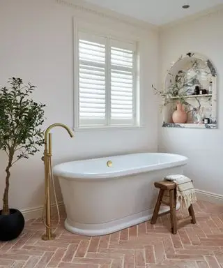 salle de bain au sol en terre cuite avec niche en marbre et baignoire autoportante