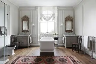 grande salle de bains avec baignoire sur pieds et miroirs vintage, store blanc