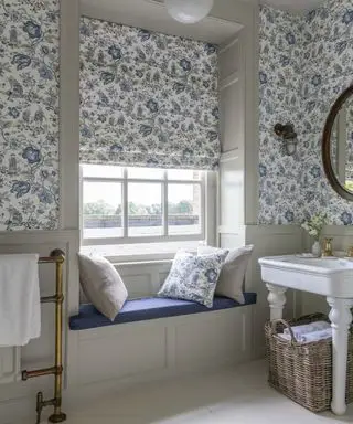 Une salle de bains avec du papier peint à motifs bleus et blancs et un siège près de la fenêtre
