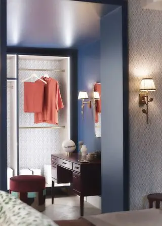 dressing/penderie avec penderie éclairée, murs bleus et luminaires et accessoires dorés