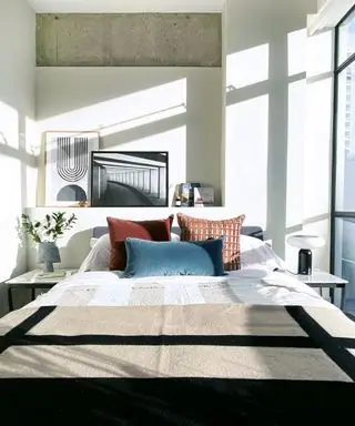 En idé om leilighetsrom med strøputer i rød oker og blågrønn, og kunstverk som lener seg på en hylle