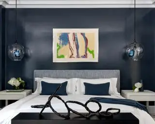 Une idée TV pour chambre à coucher avec TV dissimulée dans un meuble de bout de lit surmonté d'une sculpture abstraite contemporaine