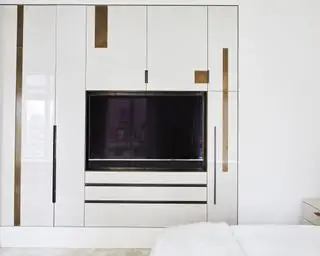 Une idée TV dans la chambre avec une TV encastrée dans des armoires blanches intégrées
