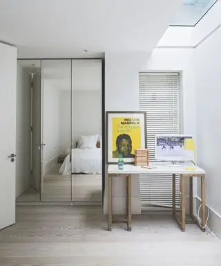 Une idée de téléviseur dans une chambre avec un bureau à domicile doté d'un moniteur et des armoires à miroir reflétant un lit blanc