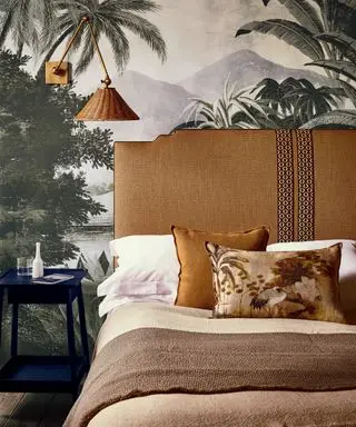 En soveværelsesfarveidé med vægmaleri og lag af tonalt brunt sengetøj og tilbehør