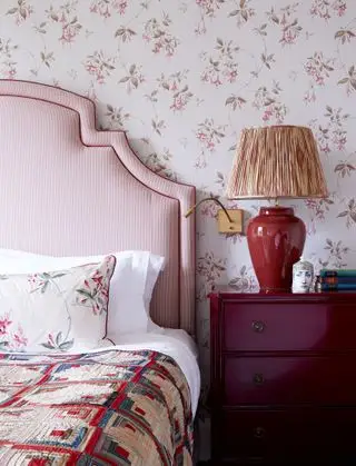 chambre avec tête de lit à rayures rouges, commode rouge, lampe rouge, papier peint à pétales rouges, jeté vintage