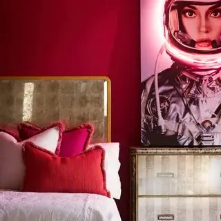 chambre rouge avec lit à rebord doré et commode assortie, œuvres d'art modernes, coussins à franges