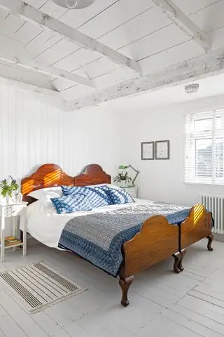 loftsrom med hvite vegger, paneltak og antikk seng