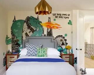 En statement-vegg i graffiti-stil med Londons skyline bak en nøytral seng og gull taklampe.