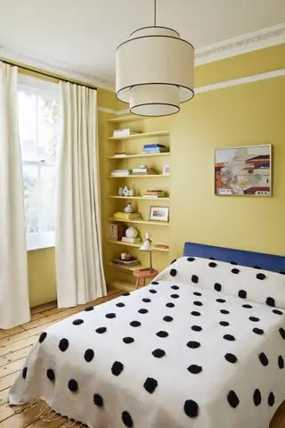 gul tenåringsjente soverom med svart og hvitt flekkteppe, hyller, kunstverk, tregulv, blå hodegjerde