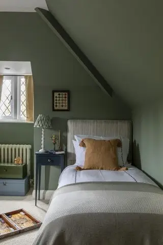 grønt loftsoverom for barn, enkeltseng, brettspill, mønstret lampeskjerm, fargede oppbevaringskister, blått sidebord